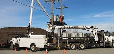 Trans Power digger derrick and boom trucks staged in an equipment yard
