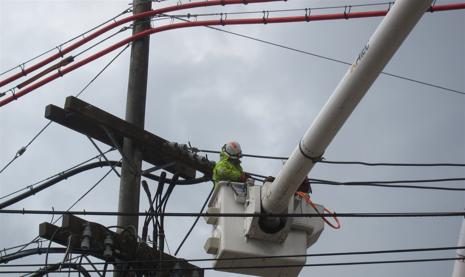 Two linemen working from an elevated bucket on an energized distribution pole
